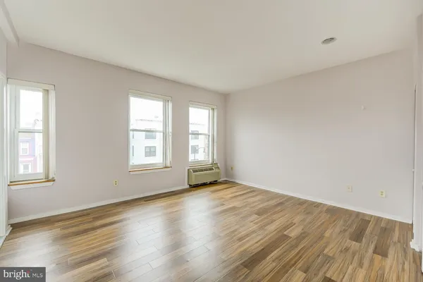 an empty room with wooden floor and windows