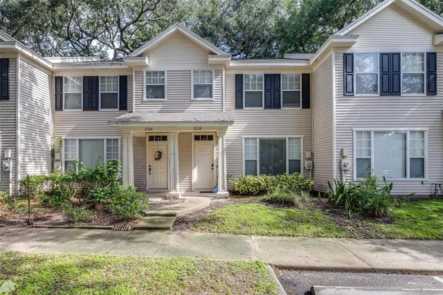a front view of a house with garden and tress