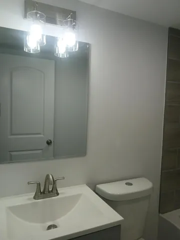 a bathroom with a toilet sink and mirror