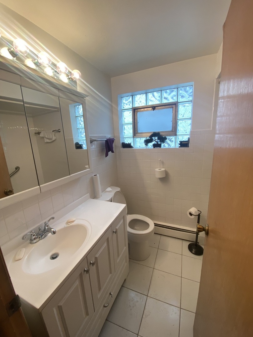 8530 South Carpenter Street, Unit 1 Chicago, IL 60620 - Photo 3 of 10 a bathroom with a sink mirror and toilet