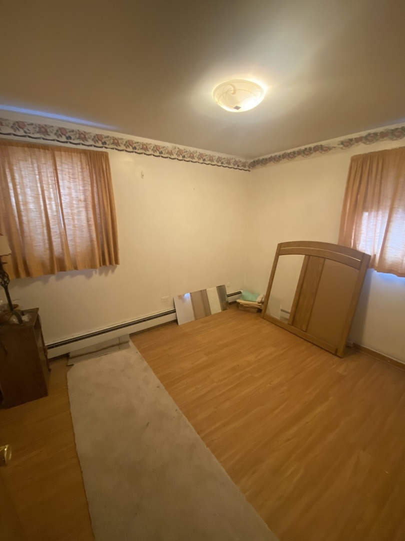 8530 South Carpenter Street, Unit 1 Chicago, IL 60620 - Photo 4 of 10 a bedroom with a bed and wooden floor