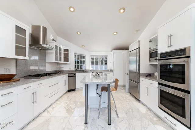 a kitchen with stainless steel appliances kitchen island granite countertop a refrigerator and a stove top oven