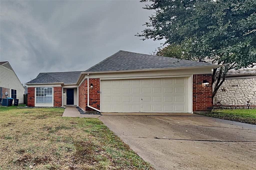 Ranch-style home featuring a shingled roof, brick siding, driveway, a front lawn, and an attached garage