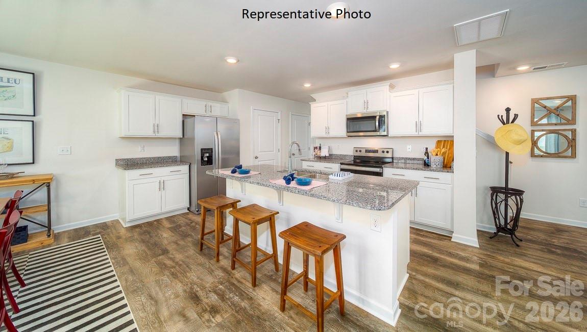 1371 Mammoth Road Hickory, NC 28602 - Photo 4 of 34 a kitchen with stainless steel appliances granite countertop a stove top oven a sink a dining table and chairs with wooden floor