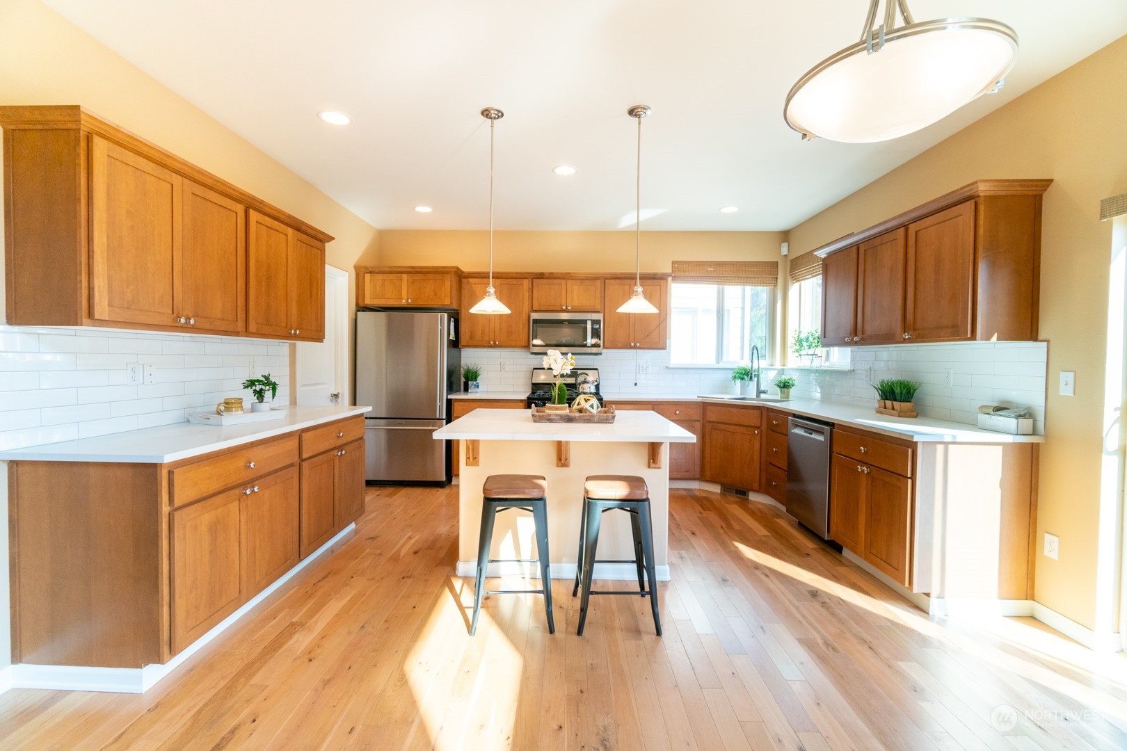 23911 22nd Avenue West Bothell, WA 98021 - Photo 10 of 27 a kitchen with stainless steel appliances kitchen island granite countertop a stove a sink a refrigerator and white cabinets with wooden floor