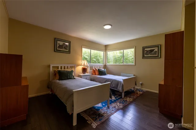a bedroom with two beds and wooden floor