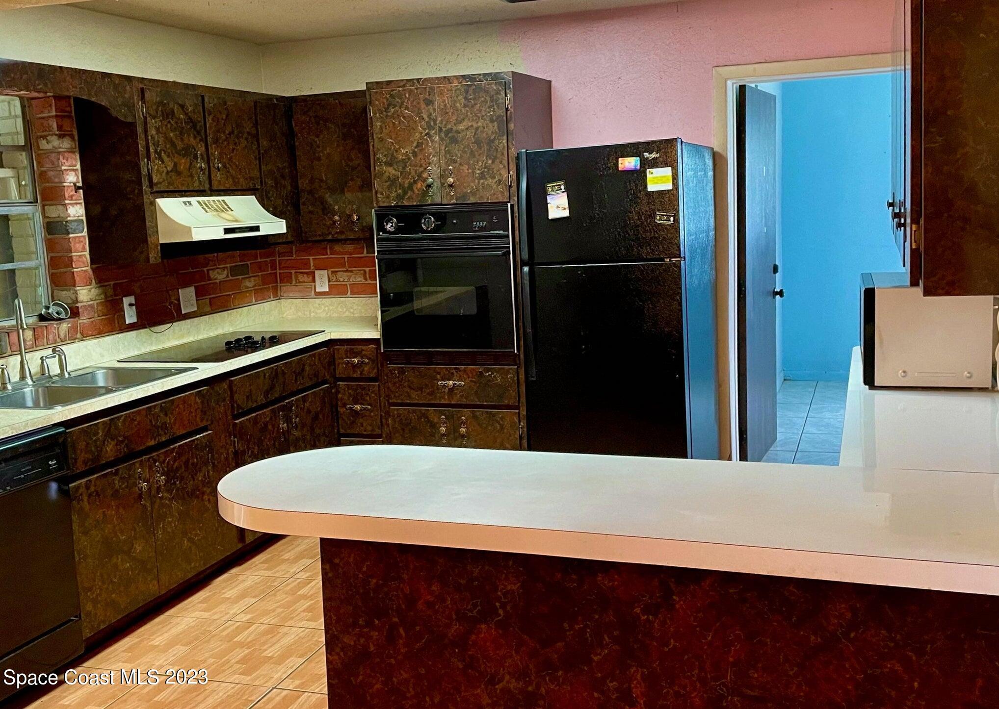 245 Richards Road Melbourne Beach, FL 32951 - Photo 4 of 18 a kitchen with stainless steel appliances kitchen island granite countertop a refrigerator a stove and a sink