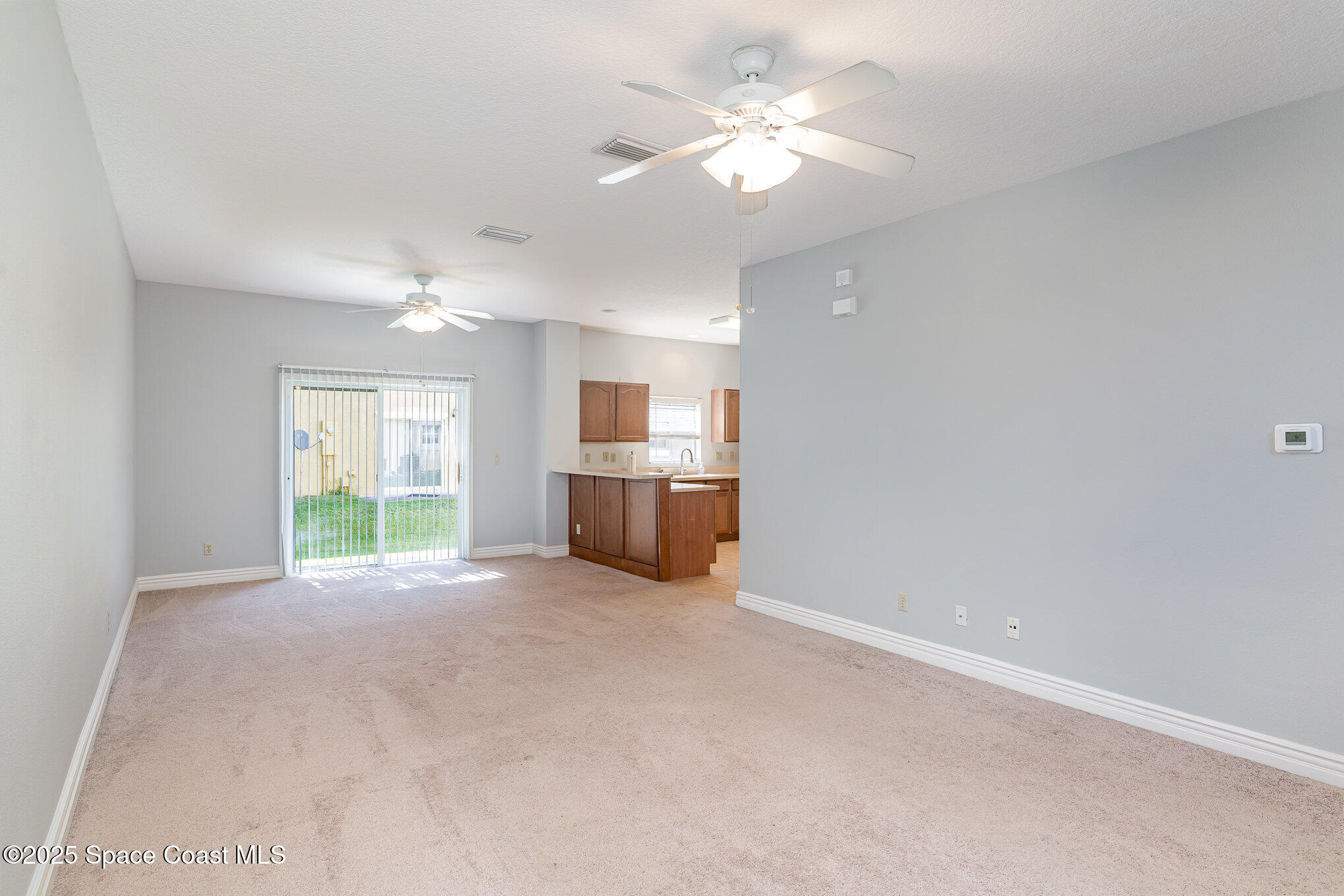 609 Cedar Side Circle Northeast Palm Bay, FL 32905 - Photo 4 of 19 an empty room with windows and ceiling fan