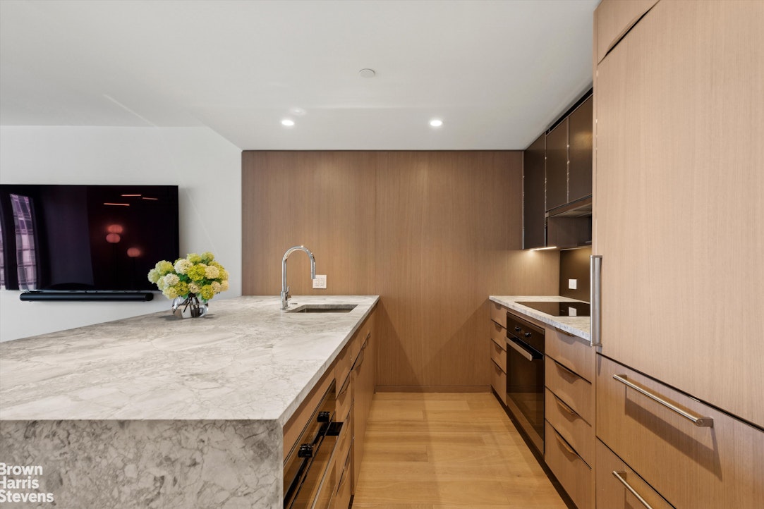 111 West 56th Street, Unit 38L Manhattan, NY 10019 - Photo 3 of 12 a kitchen with stainless steel appliances granite countertop sink stove and cabinets