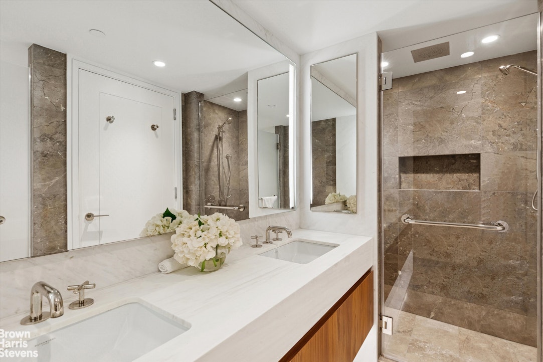 111 West 56th Street, Unit 38L Manhattan, NY 10019 - Photo 6 of 12 a bathroom with a double vanity sink mirror and shower