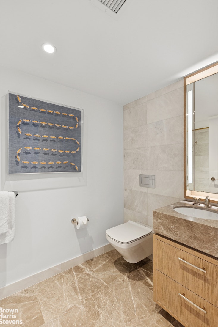 111 West 56th Street, Unit 38L Manhattan, NY 10019 - Photo 8 of 12 a bathroom with a granite countertop sink a toilet a mirror and bathtub