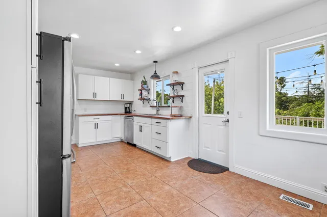 a kitchen with white cabinets and window