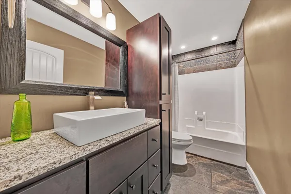 a bathroom with a granite countertop sink a toilet a mirror and bathtub