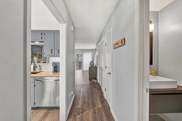 a view of a hallway with wooden floor and a kitchen