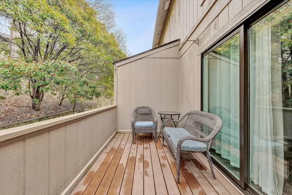 a balcony with wooden floor and outdoor seating