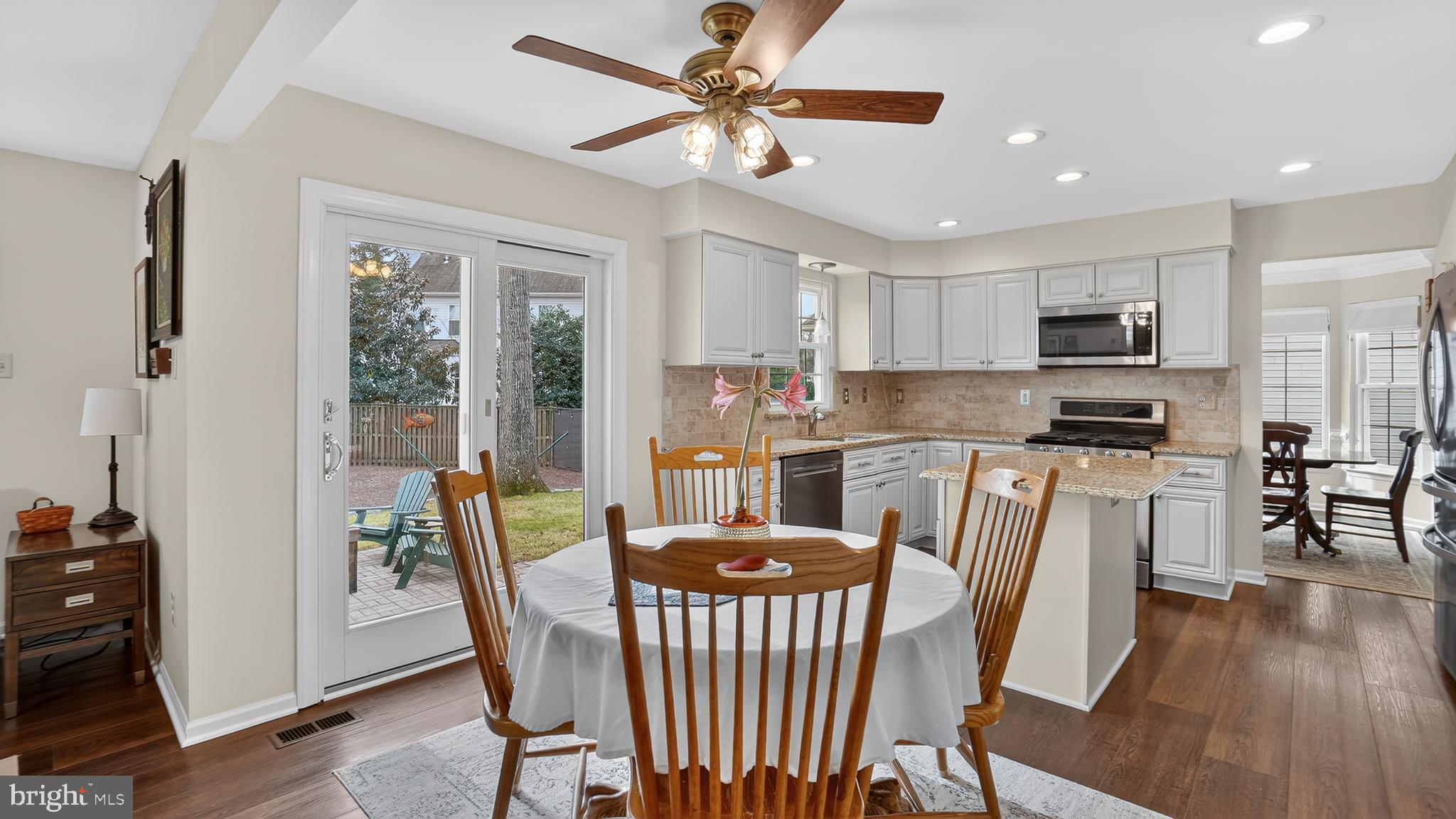 2709 Bains Court Crofton, MD 21114 - Photo 16 of 63 a kitchen with stainless steel appliances granite countertop a stove a refrigerator a microwave a dining table and chairs with wooden floor