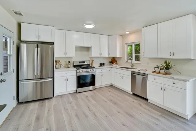 a kitchen with white cabinets stainless steel appliances and a window