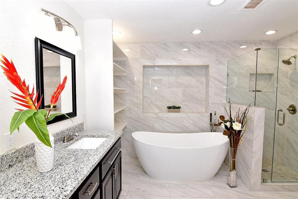 a bathroom with a granite countertop sink a mirror a bathtub and shower