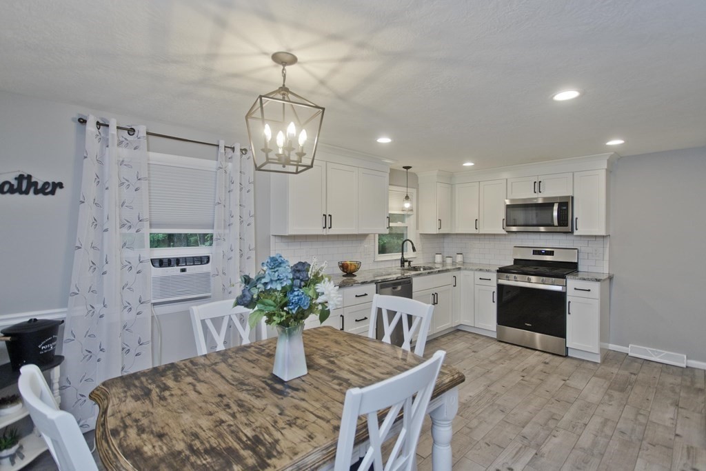 1041 Burts Pit Road Northampton, MA 01062 - Photo 7 of 22 a kitchen with stainless steel appliances granite countertop a stove top oven a refrigerator a sink dishwasher a dining table and chairs with wooden floor