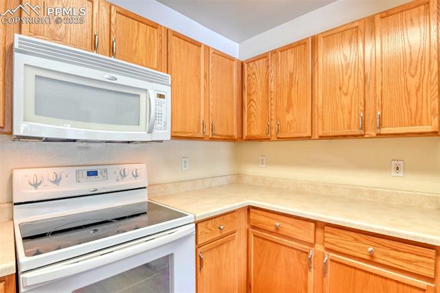 2049 Legacy Ridge View, Unit 111 Colorado Springs, CO 80910 - Photo 17 of 32 Kitchen featuring white appliances and light countertops