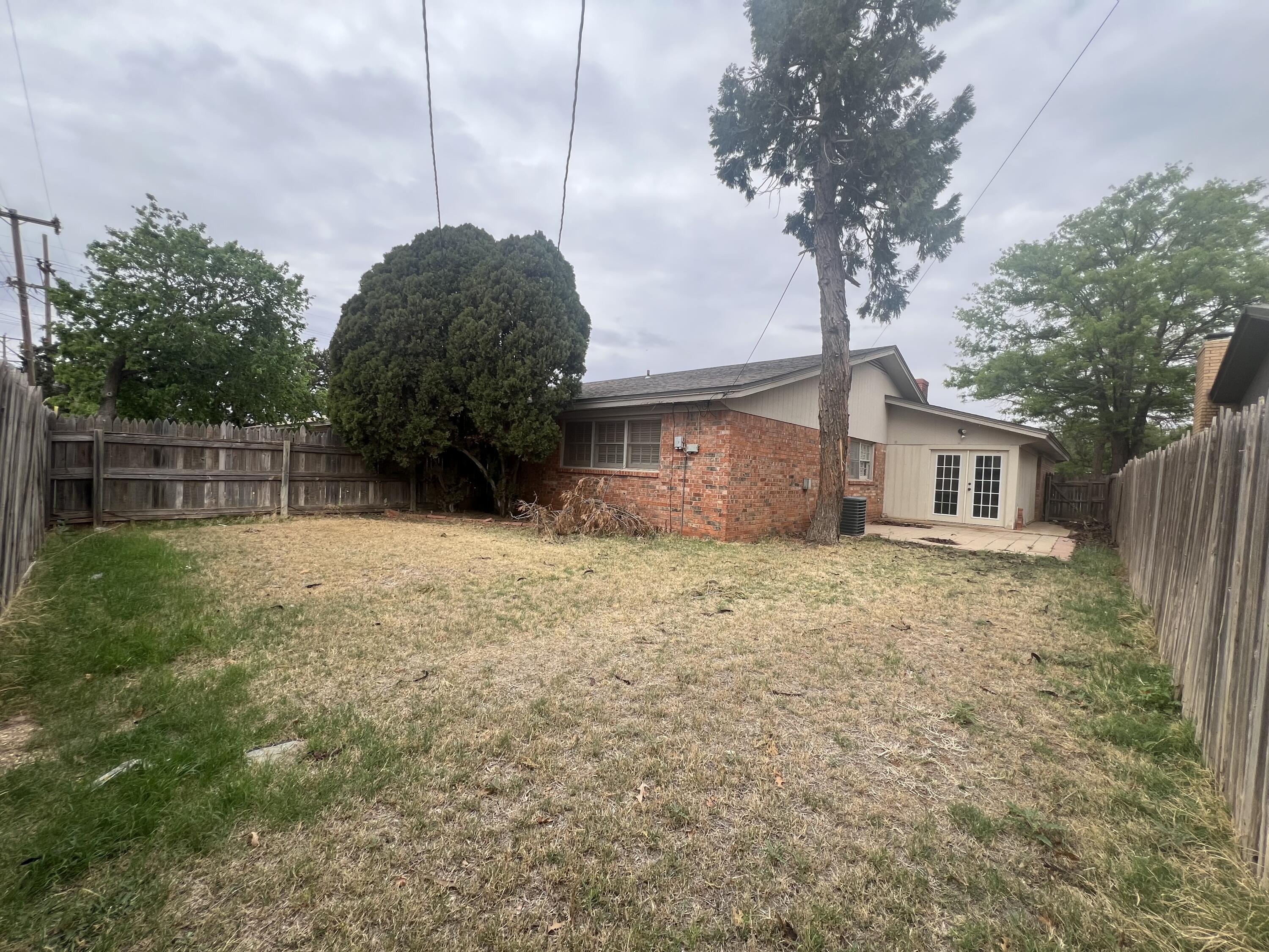 5113 13th Street, Unit A Lubbock, TX 79416 - Photo 17 of 25 a view of a house with a backyard and a tree
