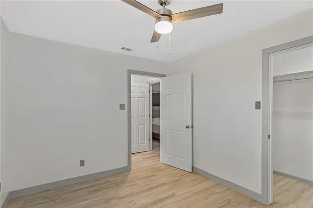 an empty room with wooden floor ceiling fan and window
