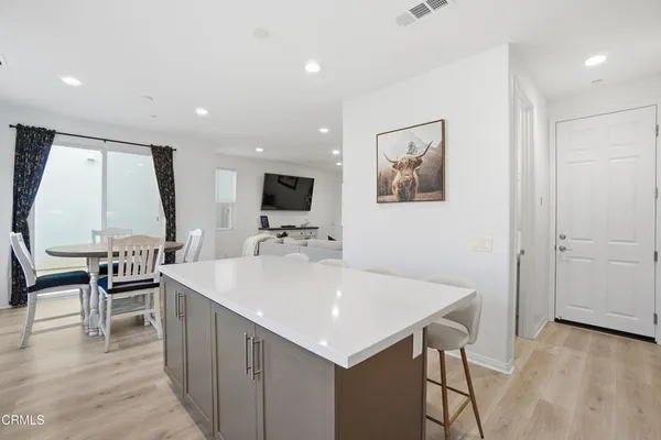 a large white kitchen with a sink a microwave a dining table and chairs