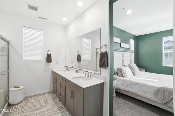 a en suite bathroom with a double vanity sink toilet and a mirror