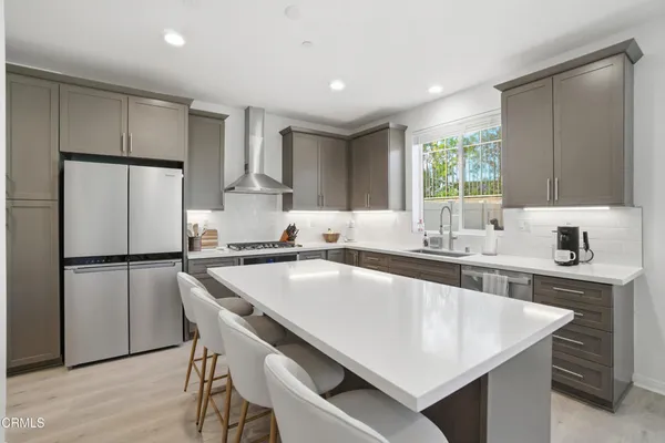 a kitchen with kitchen island a counter top space a sink stainless steel appliances and cabinets