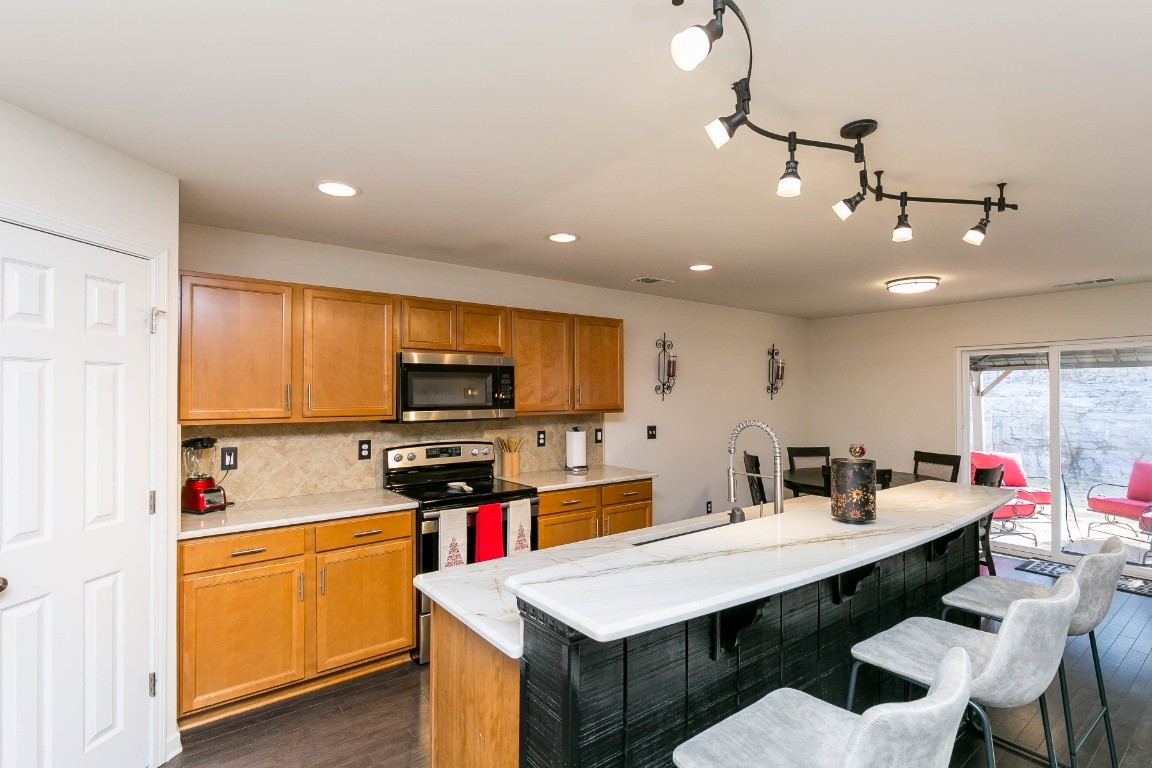 1450 Old Stone Road Lebanon, TN 37087 - Photo 8 of 24 a kitchen with stainless steel appliances kitchen island granite countertop a sink dishwasher a stove a dining table and chairs with wooden floor