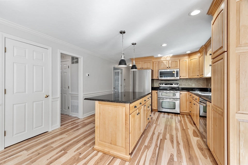 18 Sycamore Road Shrewsbury, MA 01545 - Photo 3 of 40 a kitchen with granite countertop a refrigerator stove top oven and wooden floor