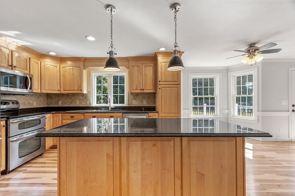 18 Sycamore Road Shrewsbury, MA 01545 - Photo 6 of 40 a kitchen with stainless steel appliances granite countertop a stove a sink and a granite counter tops with wooden floors