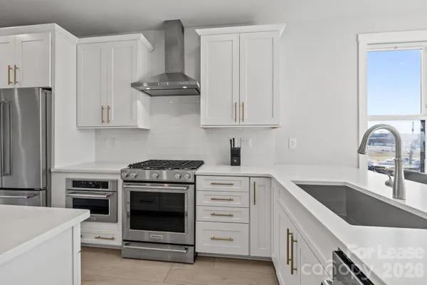 a kitchen with stainless steel appliances kitchen island granite countertop a sink a stove and a refrigerator