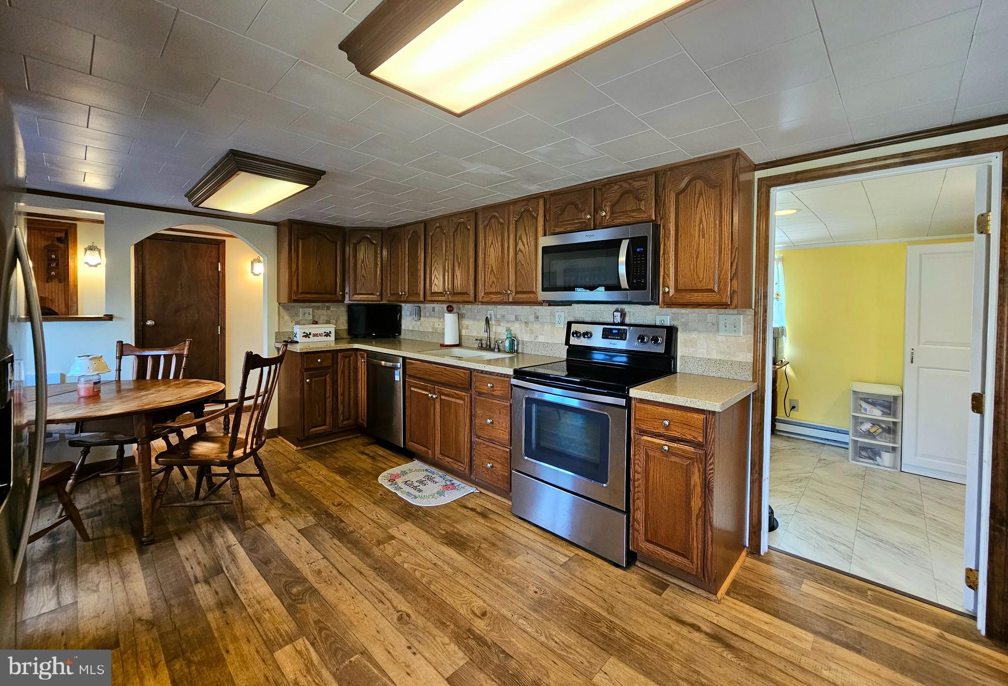 7558 Catlin Road Westover, MD 21871 - Photo 15 of 40 a kitchen with stainless steel appliances granite countertop a stove top oven a sink dishwasher a dining table and chairs with wooden floor