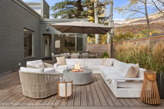 a view of a patio with couches table and chairs under an umbrella with a barbeque