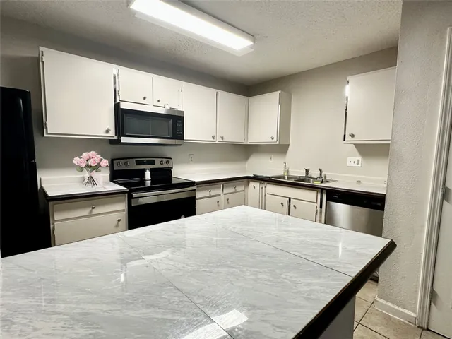 a kitchen with stainless steel appliances kitchen island granite countertop a sink dishwasher stove top oven and cabinets with wooden floor