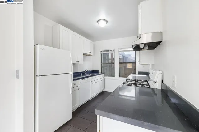 a kitchen with stainless steel appliances a refrigerator a stove a sink dishwasher and white cabinets with wooden floor