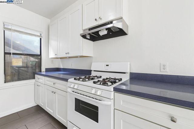 a large white kitchen with a stove a refrigerator and a kitchen island