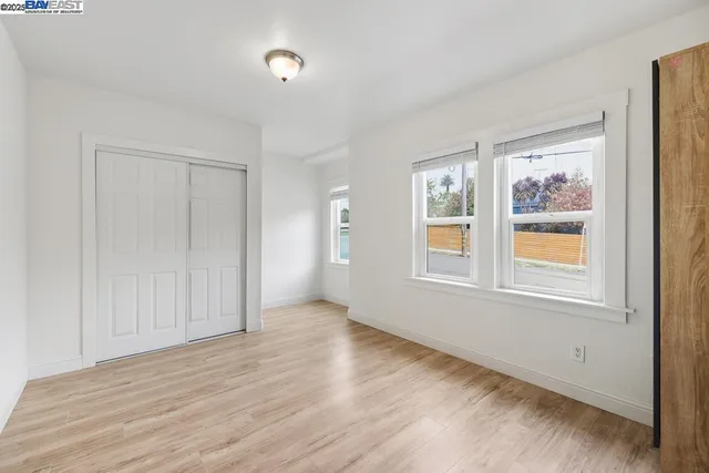 a view of an empty room with wooden floor and closet