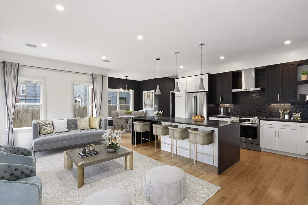 a living room with stainless steel appliances kitchen island granite countertop a refrigerator a stove a sink dishwasher and couches with wooden floor