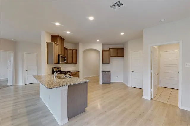 a large kitchen with stainless steel appliances kitchen island a large counter top and a wooden floors
