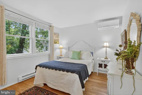 a bedroom with a bed table flowerpot and window