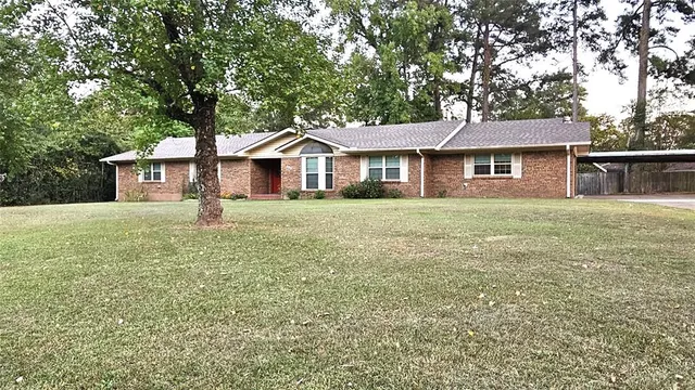 a front view of a house with a garden and trees