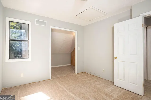 a view of an empty room with closet and a window