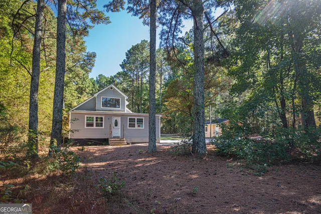 a front view of a house with a yard and large trees