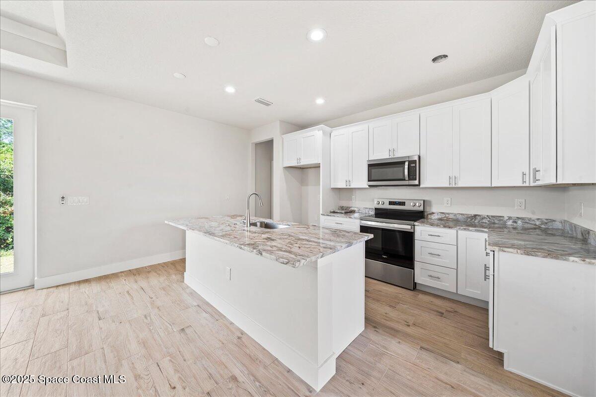1401 Wilder Road Palm Bay, FL 32909 - Photo 3 of 21 a kitchen with stainless steel appliances granite countertop a stove top oven a sink dishwasher and a refrigerator with wooden floor