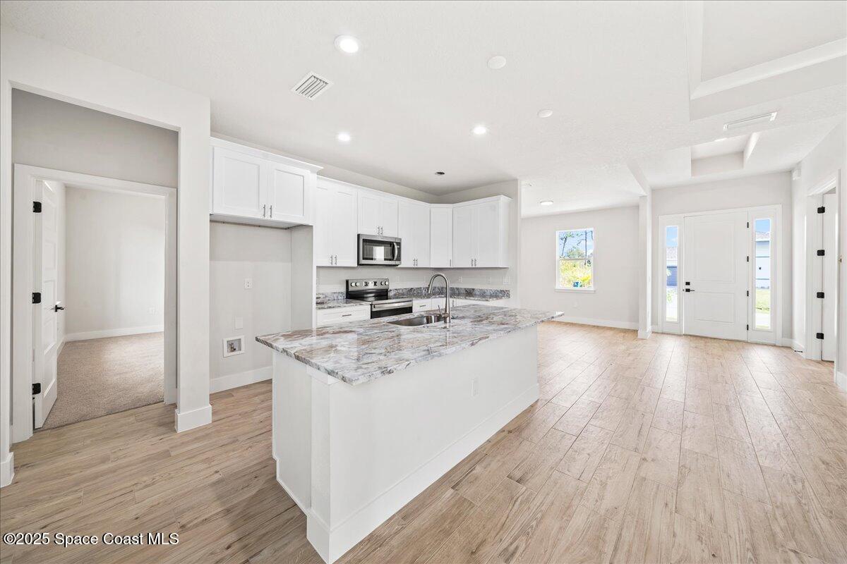 1401 Wilder Road Palm Bay, FL 32909 - Photo 4 of 21 a kitchen with stainless steel appliances granite countertop a refrigerator a sink dishwasher a stove and white countertops with wooden floor