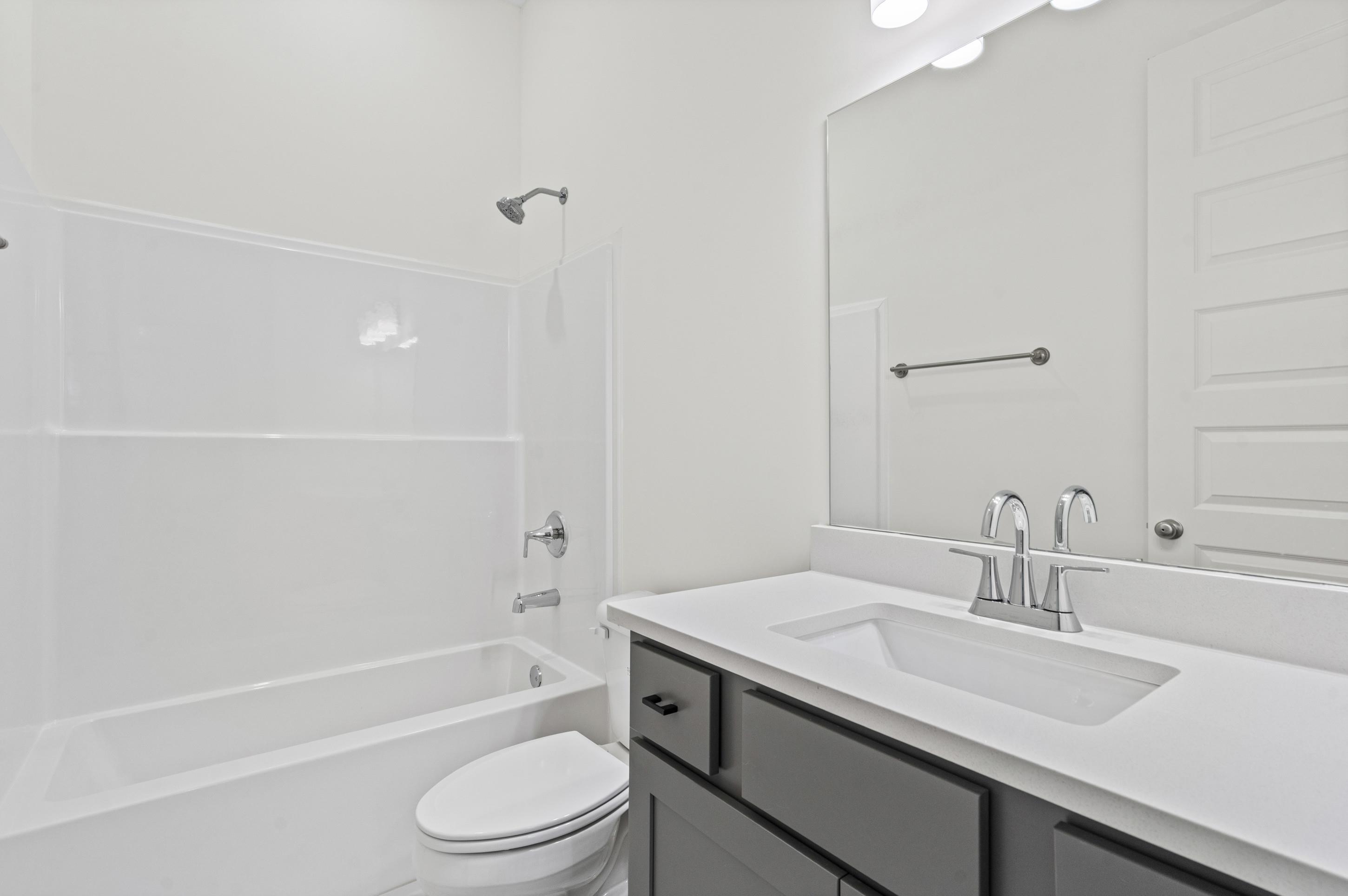 5702 Gerber Road Arlington, TN 38002 - Photo 17 of 27 Bathroom featuring a white integrated sink, gray cabinet vanity with black hardware, white tub-shower combination, polished chrome fixtures, and a large wall-mounted mirror