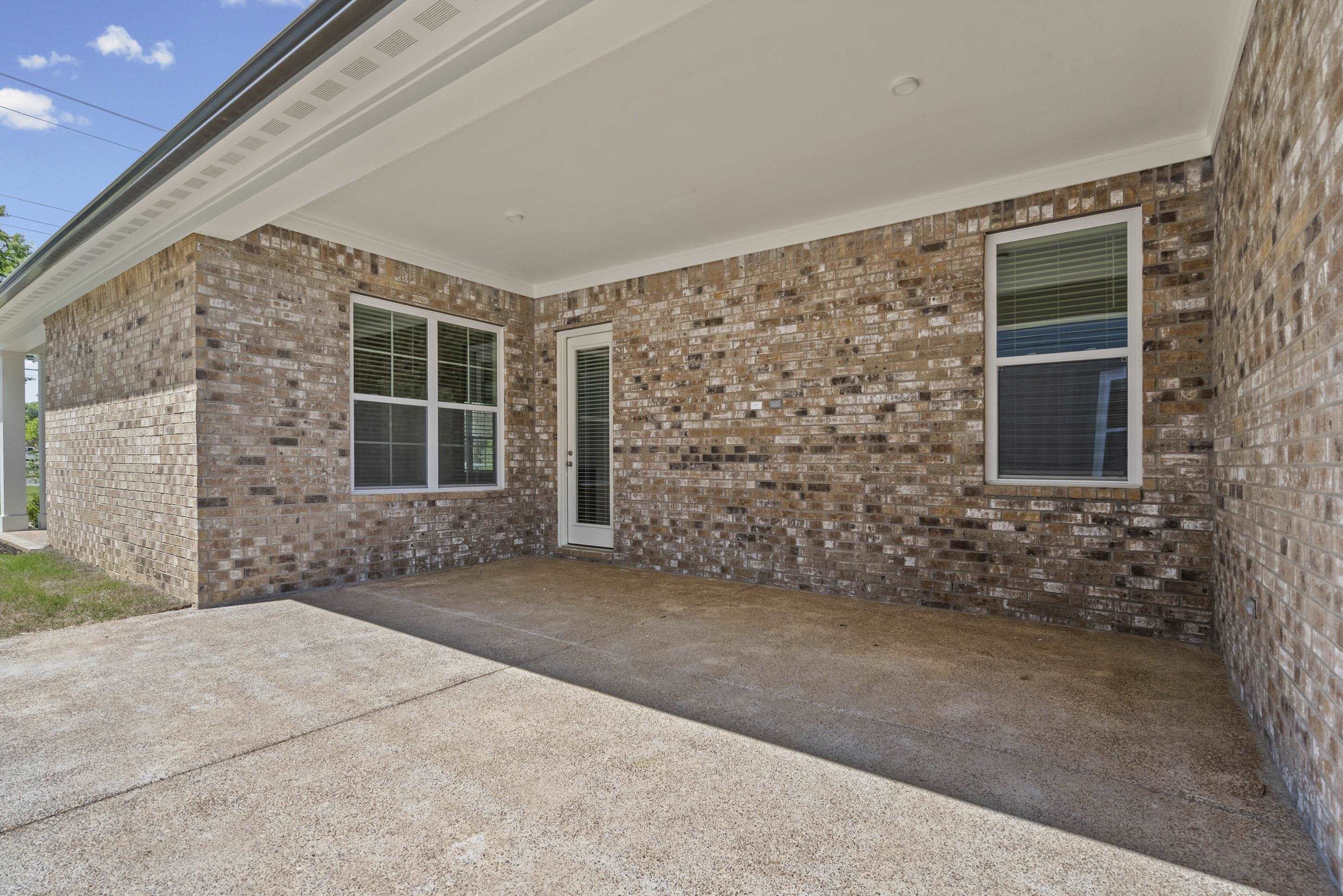 5702 Gerber Road Arlington, TN 38002 - Photo 22 of 27 Covered patio featuring a concrete slab, brick exterior, white framed windows, and a glass-paneled door