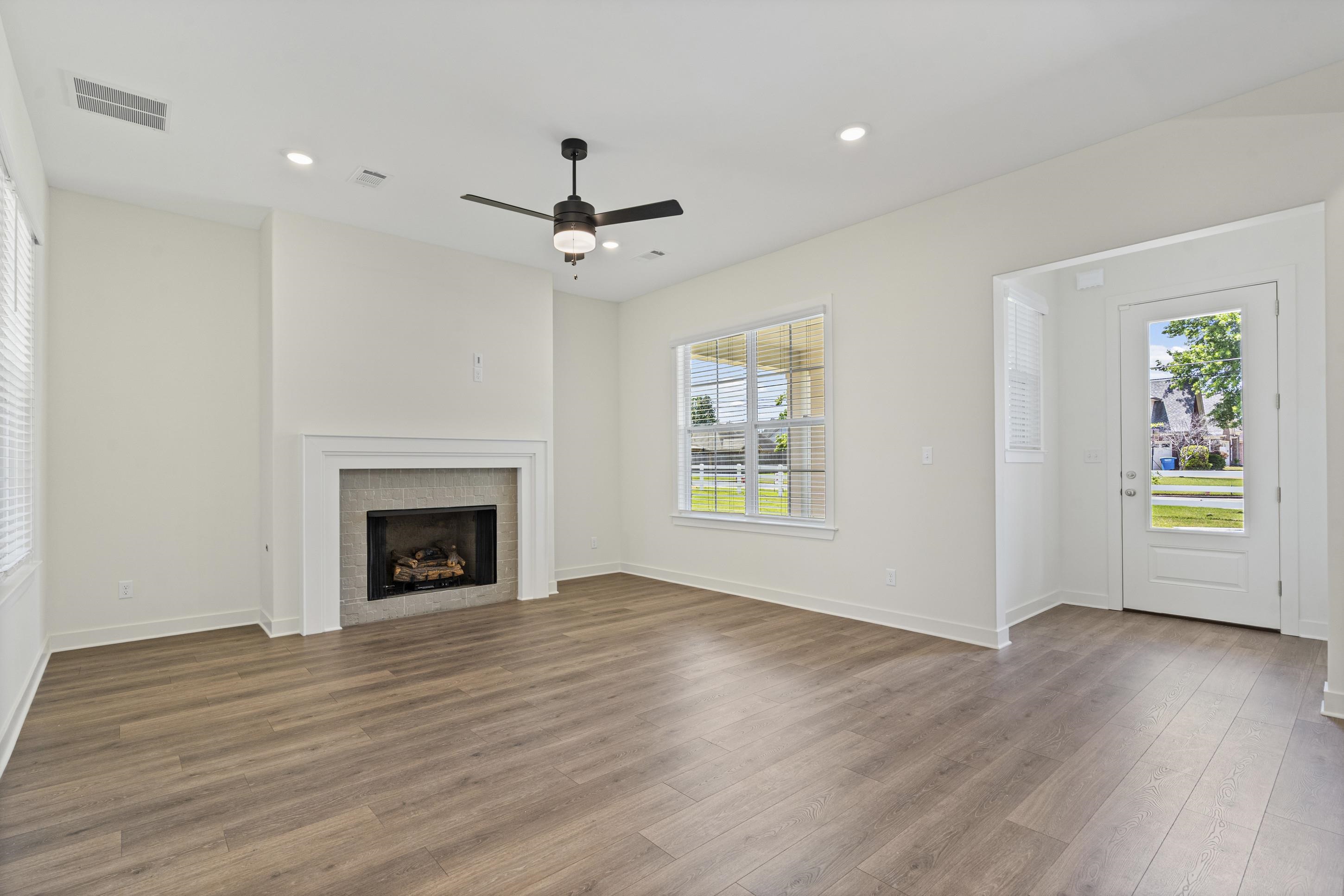 5702 Gerber Road Arlington, TN 38002 - Photo 4 of 27 Spacious living area featuring wood-finish flooring, a fireplace with a tiled surround and white mantel, a ceiling fan with integrated lighting, recessed lighting, and a glass-paneled exterior door